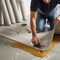someone gluing a vinyl flooring sheet to a concrete floor