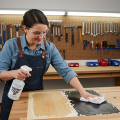 using a cloth and a bottle of 'Solvent Clean Up' to remove a stubborn patch of dried adhesive