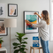 A young woman uses Glues Australia's removable adhesive strips to easily hang a picture frame in her modern living room, demonstrating a simple, damage-free decorating solution