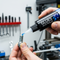 A close-up of a person applying Glues Australia's Anaerobic Glue to a metal bolt, with workshop machinery in the background. This high-performance adhesive is perfect for threadlocking, retaining, and sealing metal parts