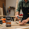 A person uses Glues Australia's Heavy Duty glue to repair wood in a workshop. The product is featured with its branding visible, showcasing its use in a durable, industrial setting