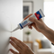 A close-up lifestyle image of a person using a tube of Glues Australia Crack Repair to easily fix a crack in a white wall, showcasing the product's effectiveness for home DIY and building repairs