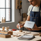  image showing a person crafting in a modern, sunlit workshop. The focus is on a stylish tin of adhesive from the "Tin" collection by Glues Australia, being used to glue a small wooden object